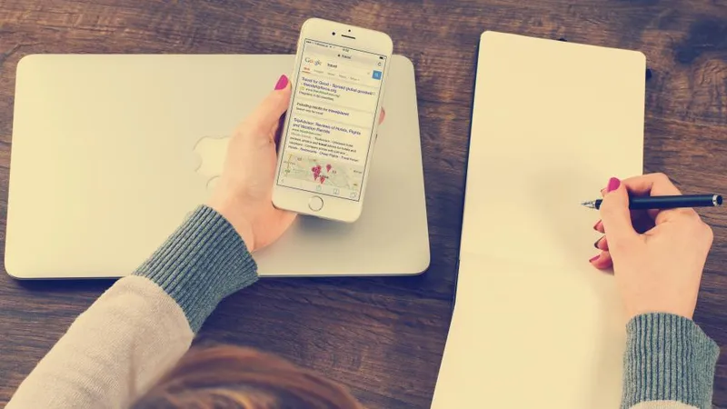 Search results on a phone beside a notebook