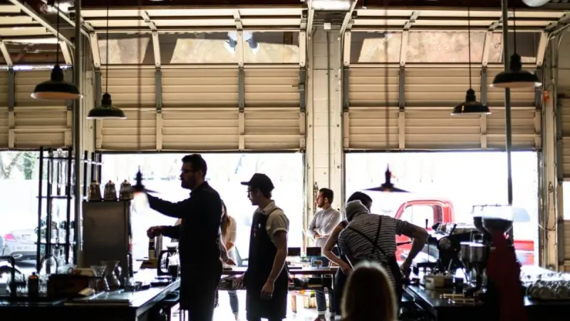 A busy coffee shop counter with baristas working and customers waiting
