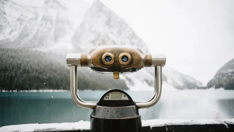 Coin-operated viewpoint binoculars facing a mountain lake
