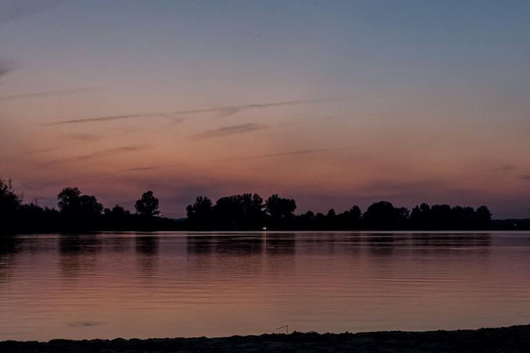 Creve Coeur Lake at sunset, the far shore's trees silhouetted against a fading orange sky.